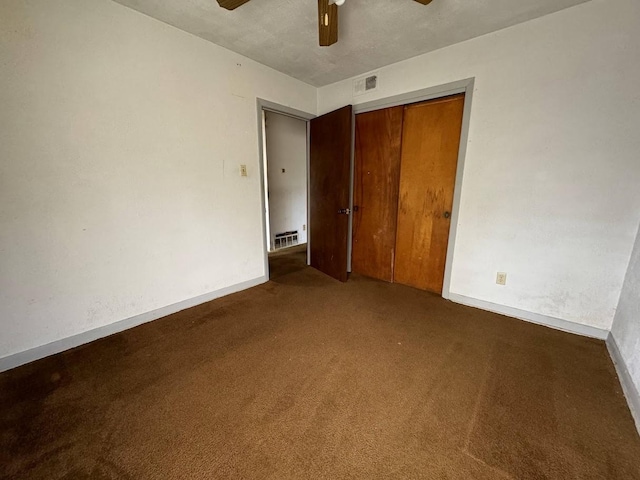 unfurnished bedroom with a textured ceiling, a closet, dark carpet, and ceiling fan