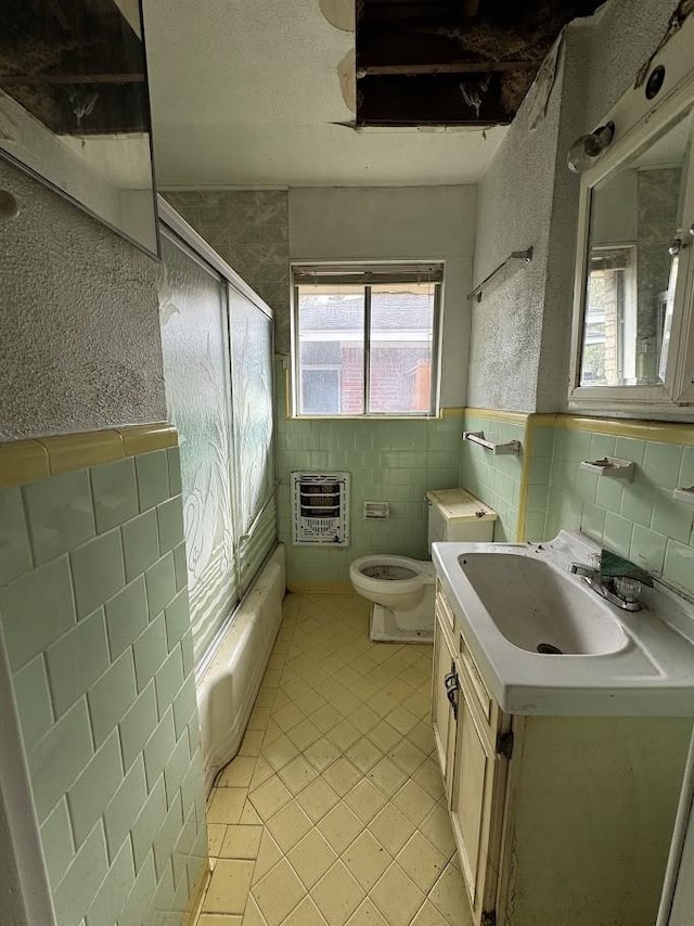 bathroom with tile patterned flooring, heating unit, toilet, vanity, and tile walls