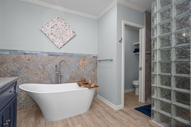 bathroom featuring a bathing tub, hardwood / wood-style floors, toilet, vanity, and ornamental molding