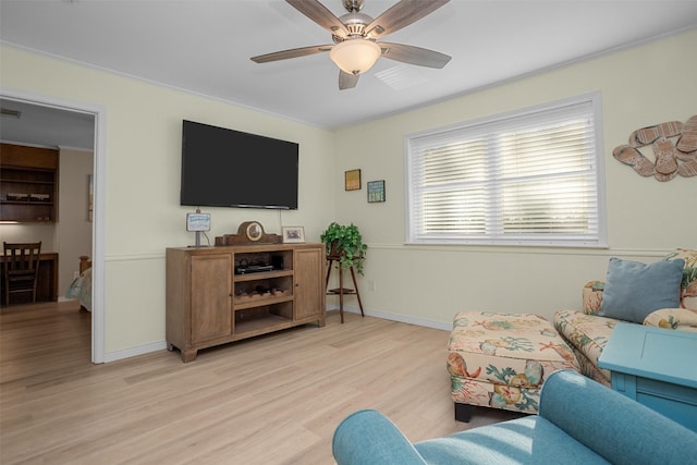 living room featuring ceiling fan, light wood-type flooring, and crown molding