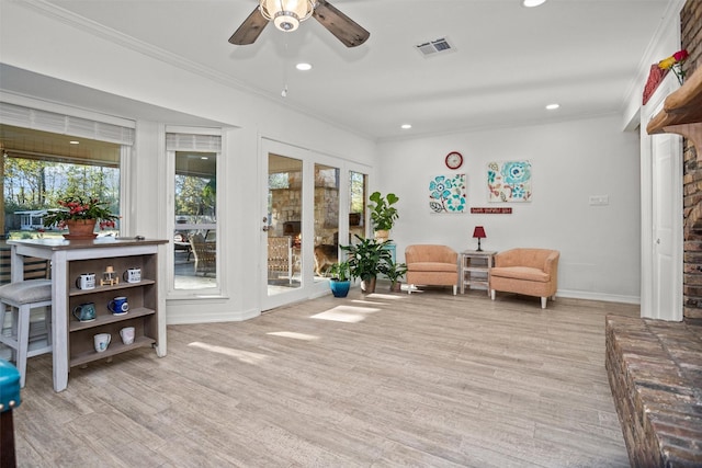 living area with light wood-type flooring, crown molding, and a healthy amount of sunlight