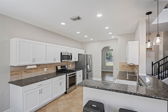 kitchen with sink, decorative light fixtures, kitchen peninsula, stainless steel appliances, and white cabinets