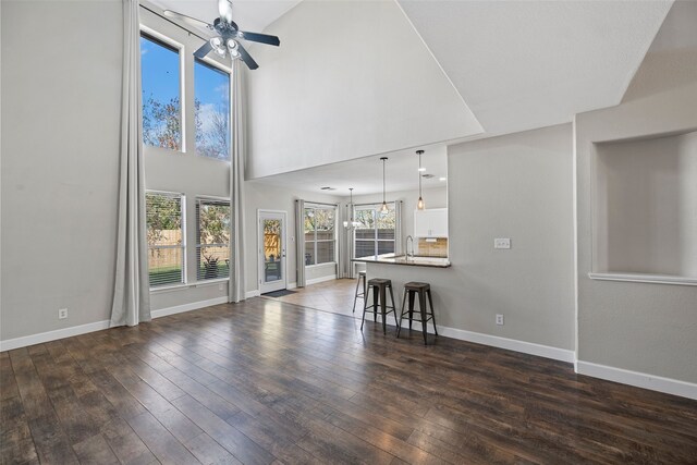 unfurnished living room with dark wood-type flooring, ceiling fan, plenty of natural light, and sink