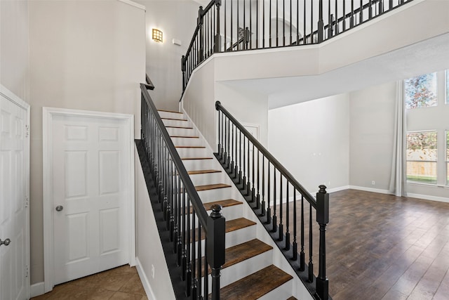 stairs with hardwood / wood-style flooring and a towering ceiling