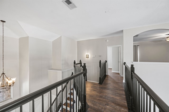 hallway featuring an inviting chandelier and dark wood-type flooring