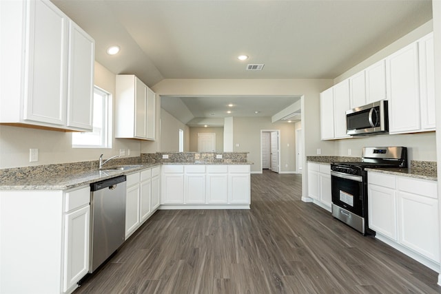 kitchen featuring light stone countertops, appliances with stainless steel finishes, white cabinetry, and dark wood-type flooring