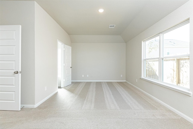 empty room with light colored carpet and vaulted ceiling