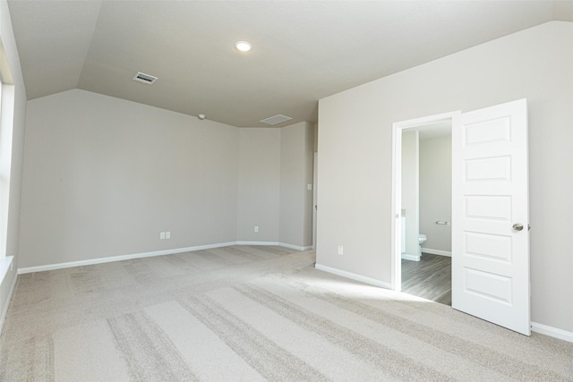 unfurnished bedroom with carpet floors, connected bathroom, and vaulted ceiling