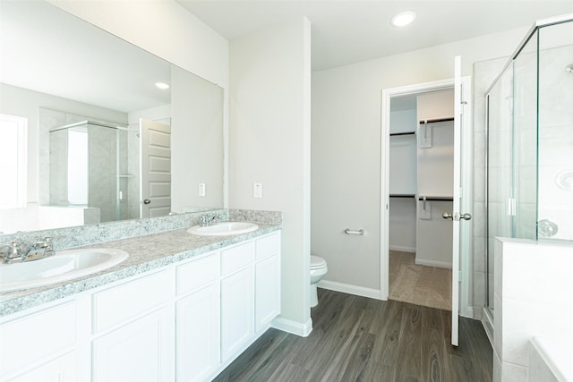 bathroom featuring toilet, vanity, an enclosed shower, and hardwood / wood-style flooring