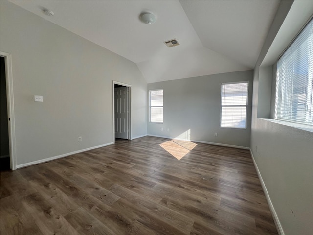 empty room featuring vaulted ceiling and dark wood-type flooring