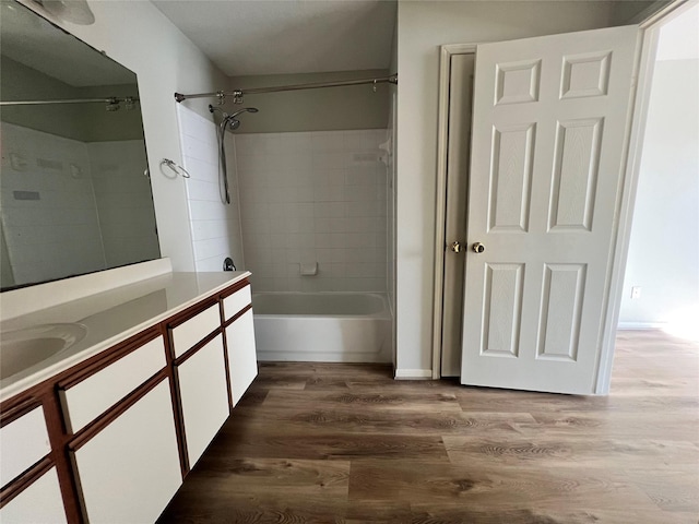 bathroom with hardwood / wood-style flooring, vanity, and tiled shower / bath combo