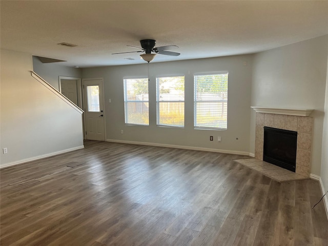 unfurnished living room with a tiled fireplace, ceiling fan, and dark hardwood / wood-style flooring