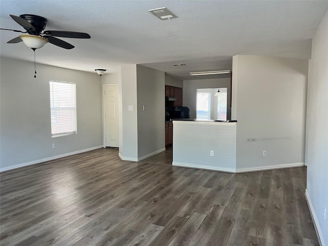 empty room featuring ceiling fan, dark hardwood / wood-style flooring, a textured ceiling, and a wealth of natural light