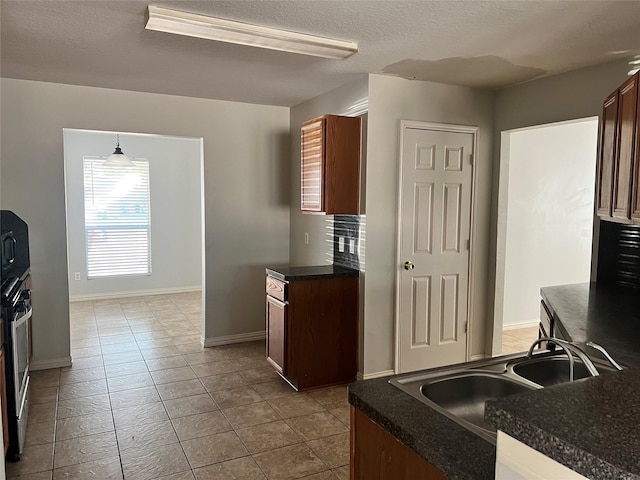 kitchen featuring stainless steel oven, a textured ceiling, sink, hanging light fixtures, and light tile patterned flooring