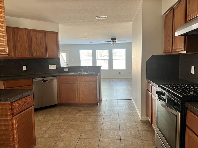 kitchen with decorative backsplash, ceiling fan, light tile patterned floors, stainless steel appliances, and extractor fan