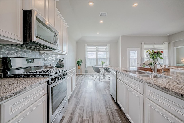 kitchen with stainless steel appliances, white cabinetry, sink, and a healthy amount of sunlight