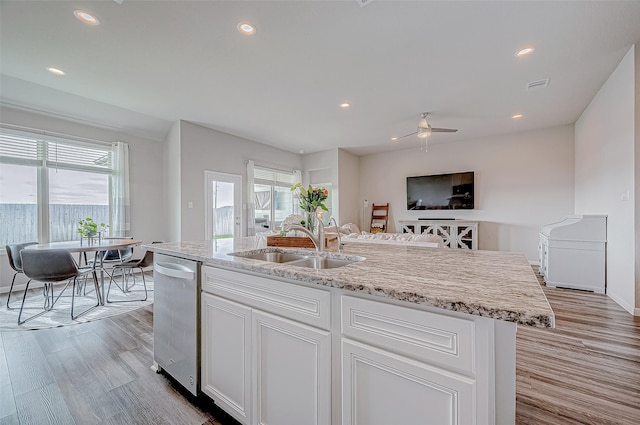 kitchen with sink, light hardwood / wood-style flooring, white cabinetry, a kitchen island with sink, and light stone countertops