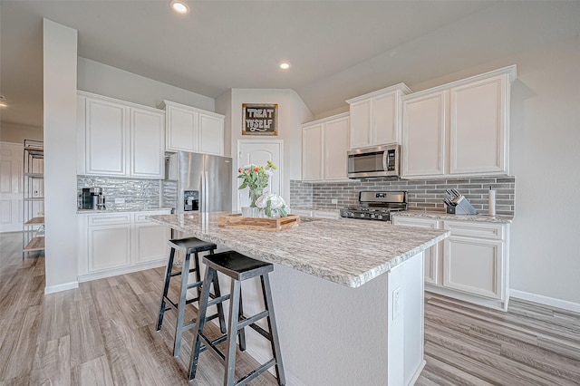 kitchen with white cabinetry, stainless steel appliances, and an island with sink