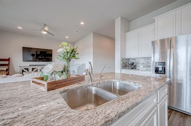 kitchen featuring sink, dark wood-type flooring, white cabinetry, stainless steel refrigerator with ice dispenser, and light stone counters