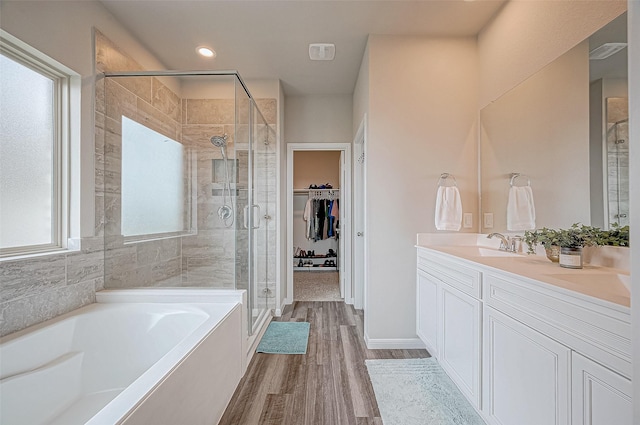 bathroom with wood-type flooring, vanity, and plus walk in shower