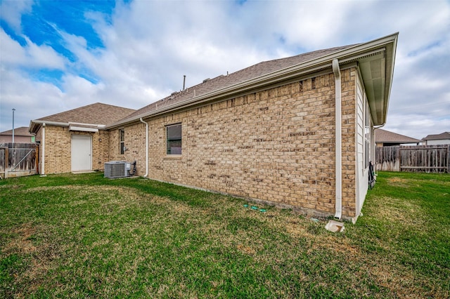 rear view of property with central AC unit and a lawn