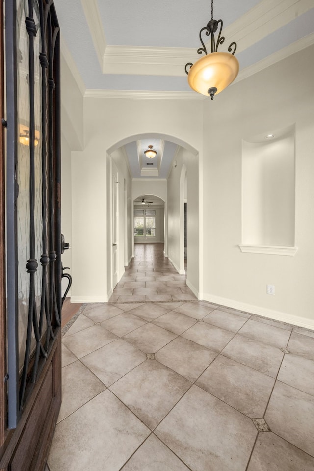 corridor with a raised ceiling, light tile patterned floors, and ornamental molding