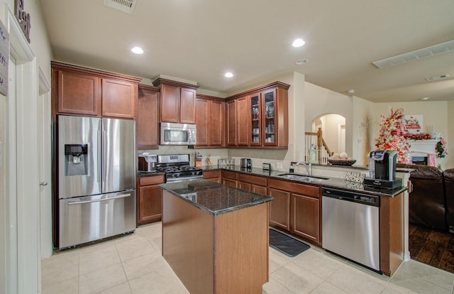 kitchen featuring a center island, sink, light hardwood / wood-style flooring, dark stone countertops, and stainless steel appliances