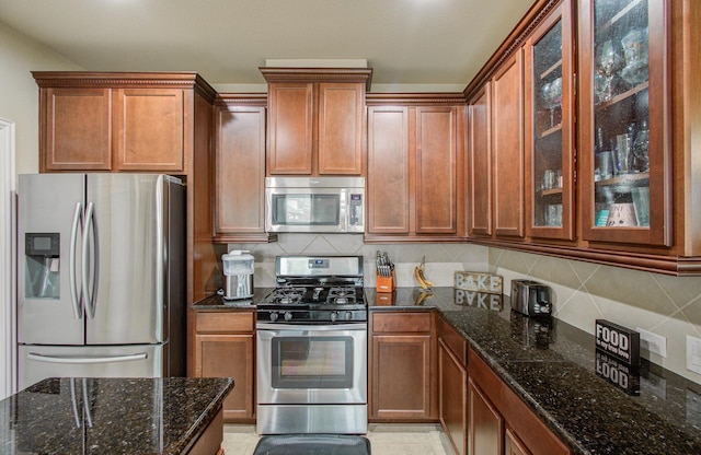 kitchen featuring dark stone countertops, appliances with stainless steel finishes, and tasteful backsplash