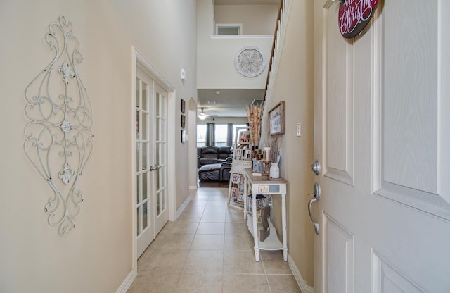 foyer entrance with ceiling fan, french doors, light tile patterned floors, and a high ceiling