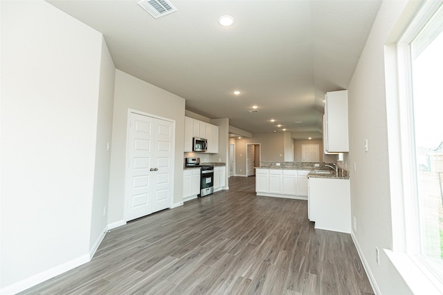 kitchen with kitchen peninsula, stainless steel appliances, sink, wood-type flooring, and white cabinetry