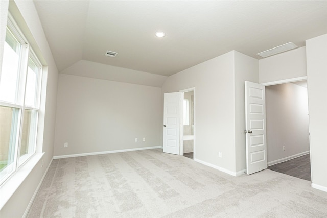 unfurnished bedroom featuring light colored carpet and lofted ceiling