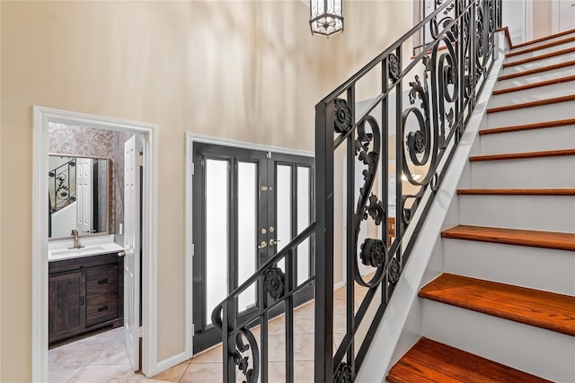 stairs with tile patterned floors, sink, and a high ceiling