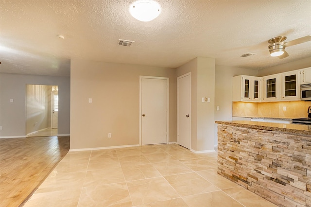 kitchen featuring light stone countertops, a textured ceiling, light hardwood / wood-style flooring, range, and white cabinetry