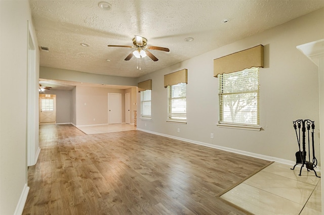 empty room featuring a textured ceiling, light hardwood / wood-style flooring, and a wealth of natural light