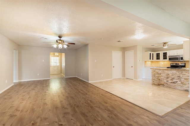 unfurnished living room with a textured ceiling and light hardwood / wood-style flooring