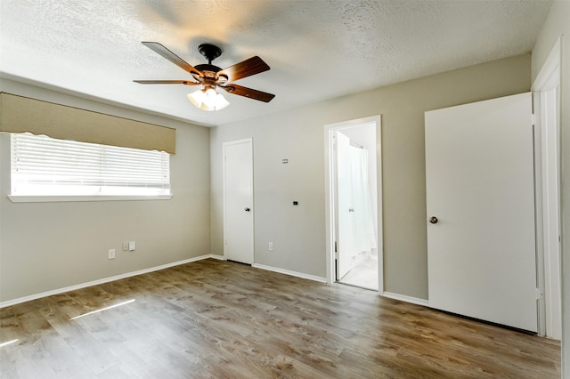 unfurnished bedroom featuring a textured ceiling, light wood-type flooring, ceiling fan, and connected bathroom