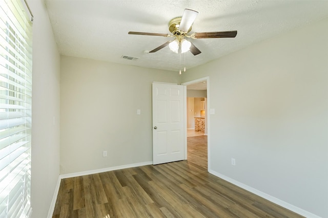 empty room featuring ceiling fan, dark hardwood / wood-style flooring, and a textured ceiling