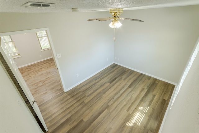 empty room with a textured ceiling, hardwood / wood-style flooring, and ceiling fan