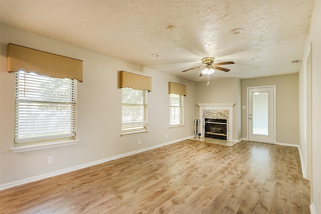 unfurnished living room with a textured ceiling, plenty of natural light, a fireplace, and light hardwood / wood-style flooring