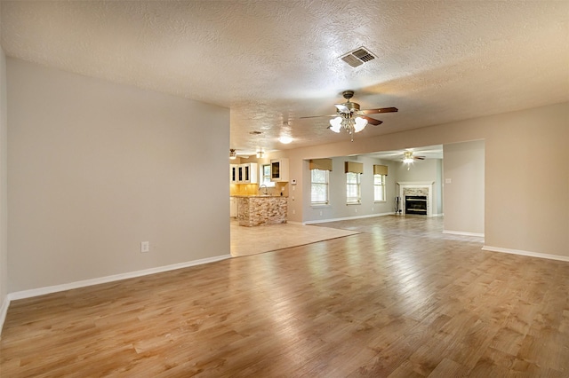 unfurnished living room featuring a textured ceiling, light hardwood / wood-style flooring, and ceiling fan