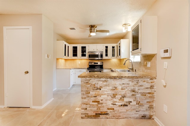 kitchen with sink, stainless steel appliances, kitchen peninsula, a textured ceiling, and white cabinets