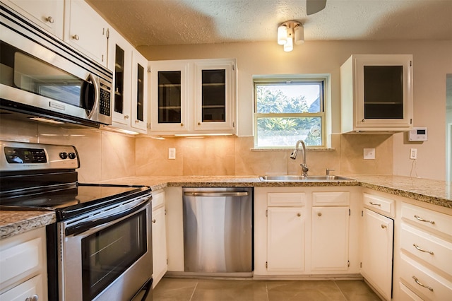 kitchen with white cabinets, light tile patterned floors, stainless steel appliances, and sink