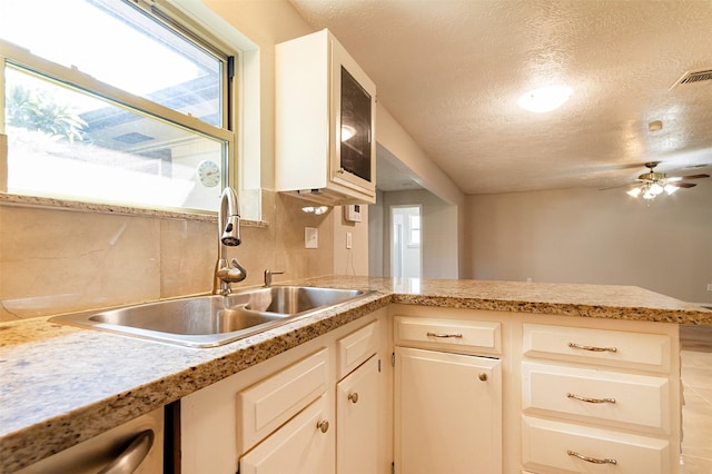 kitchen featuring decorative backsplash, a textured ceiling, ceiling fan, sink, and white cabinets