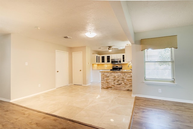 kitchen featuring white cabinetry, stainless steel appliances, a textured ceiling, and light wood-type flooring