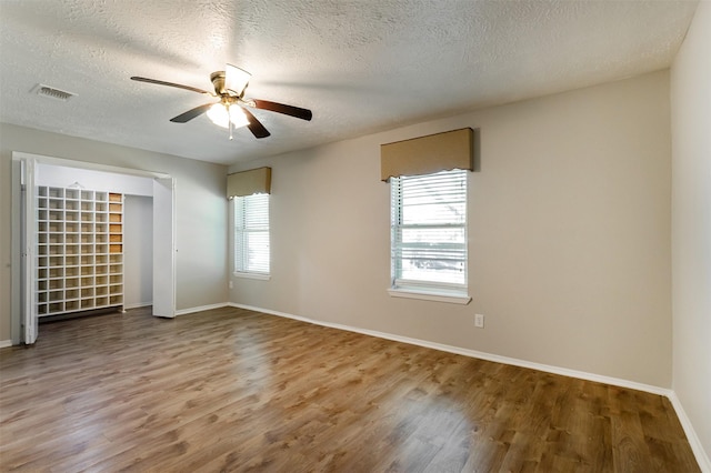 unfurnished room featuring wood-type flooring, a textured ceiling, and plenty of natural light