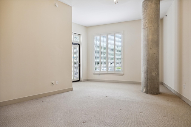 unfurnished room with decorative columns and light carpet