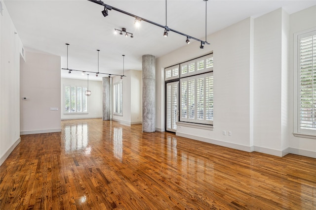 unfurnished living room featuring hardwood / wood-style flooring, plenty of natural light, and track lighting