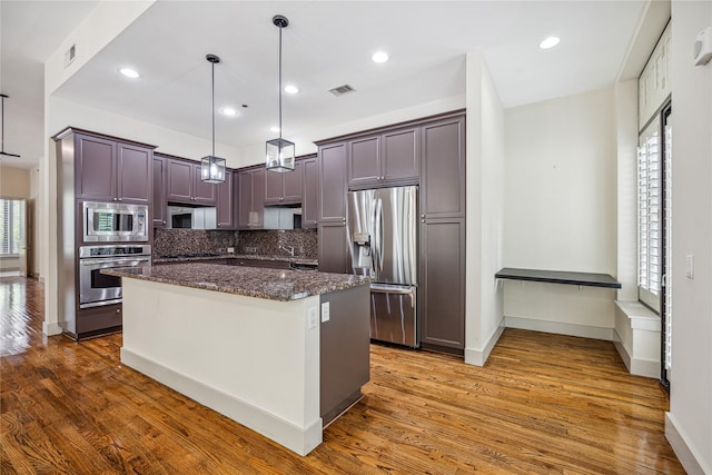 kitchen with appliances with stainless steel finishes, a center island, plenty of natural light, and pendant lighting