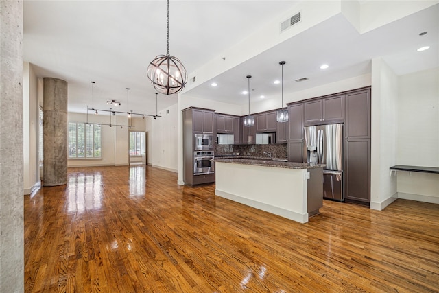 kitchen featuring pendant lighting, a center island, dark hardwood / wood-style floors, appliances with stainless steel finishes, and tasteful backsplash