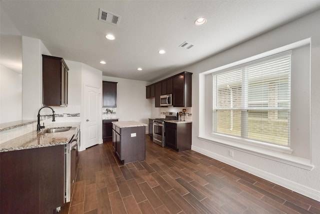 kitchen featuring sink, dark hardwood / wood-style floors, a kitchen island, dark brown cabinetry, and stainless steel appliances